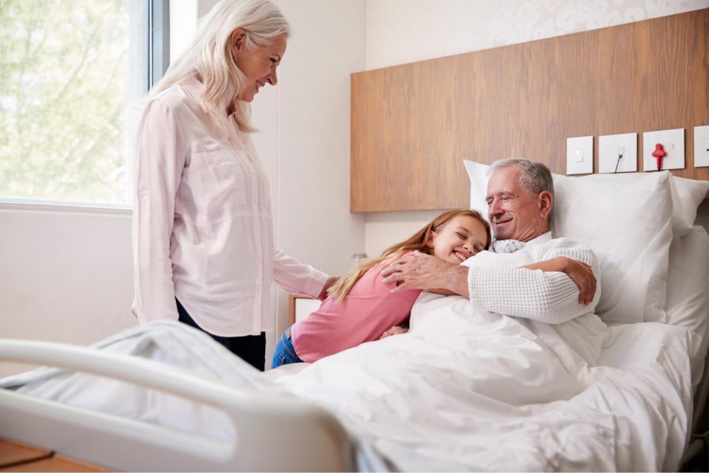 Granddaughter hugging grandfather on a medical bed